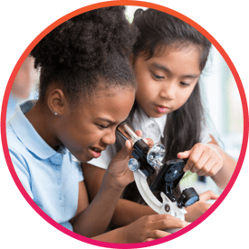 Two girls in a private school lab class looking into a microscope