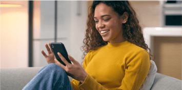 woman on her couch using mobile device
