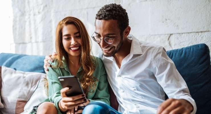 Couple sitting on couch looking at a mobile phone