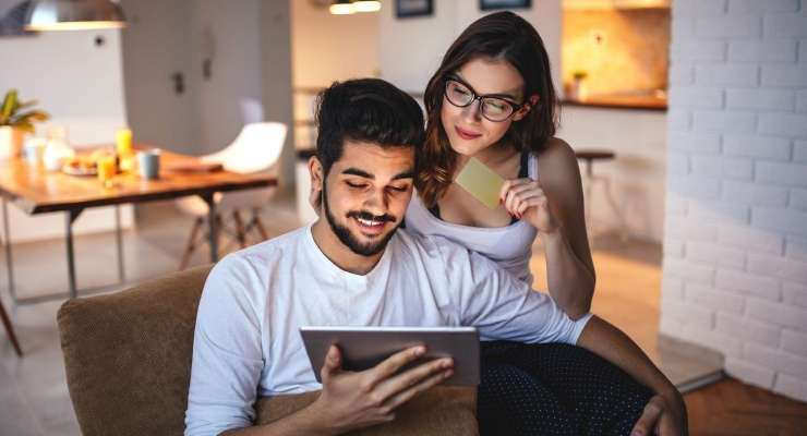 Couple using a gift card to shop online at home