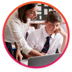 Private school teacher helping student on laptop in classroom