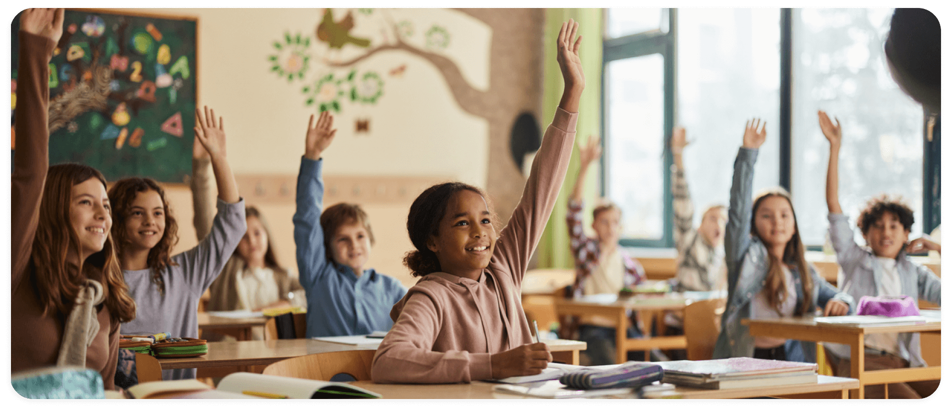 children in a classroom raising their hands