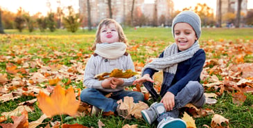 two little boys playing in fall leaves in a park
