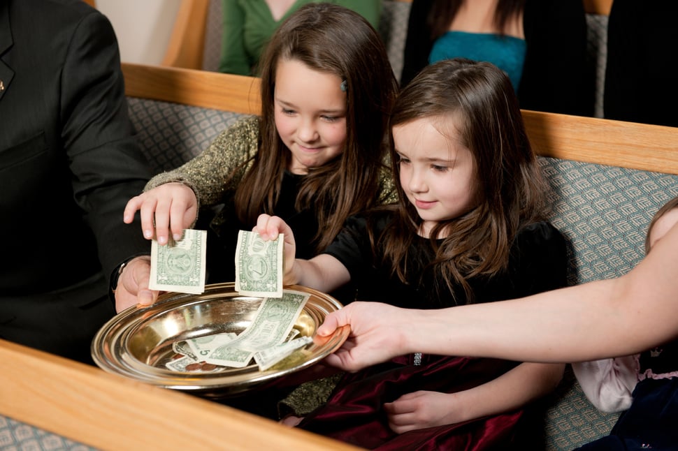 Little girls placing money in the offering plate at church