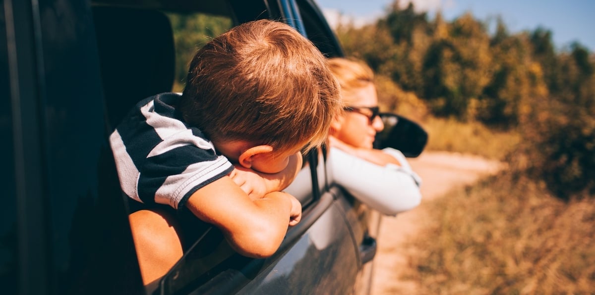 mom and kid looking out the car window on a family road trip
