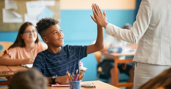 elementary school student high fiving teacher