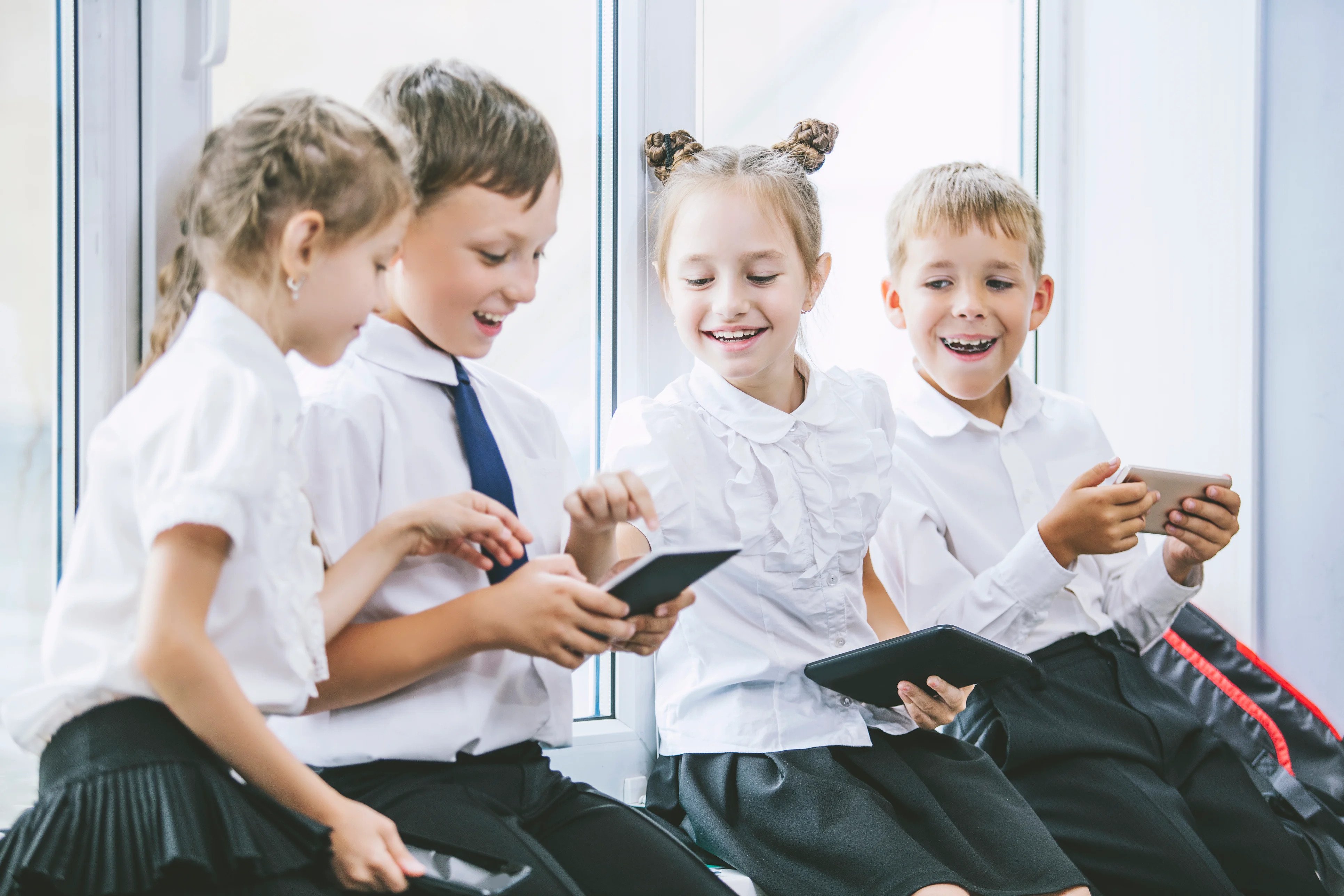 private school students sitting together using their devices