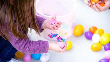 girl opening plastic easter eggs with candy