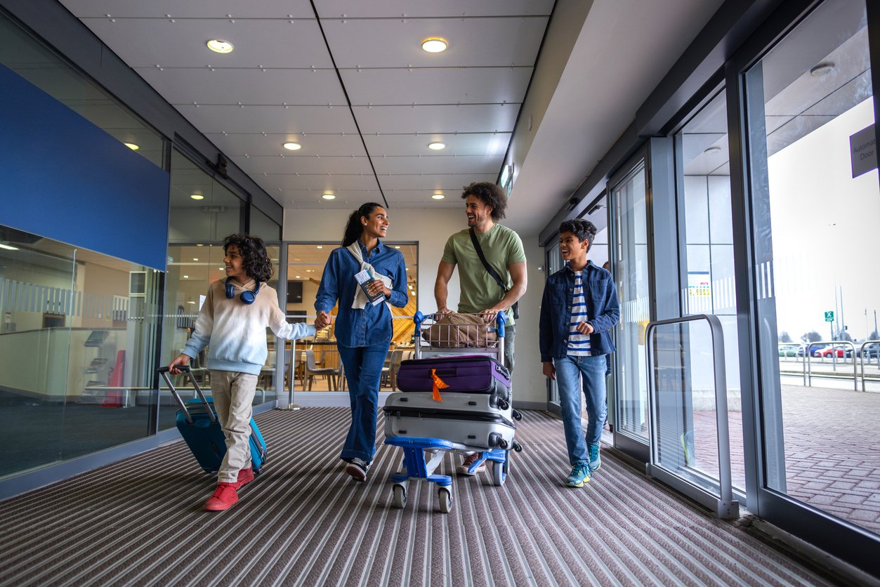 family of four carrying luggage through a hotel