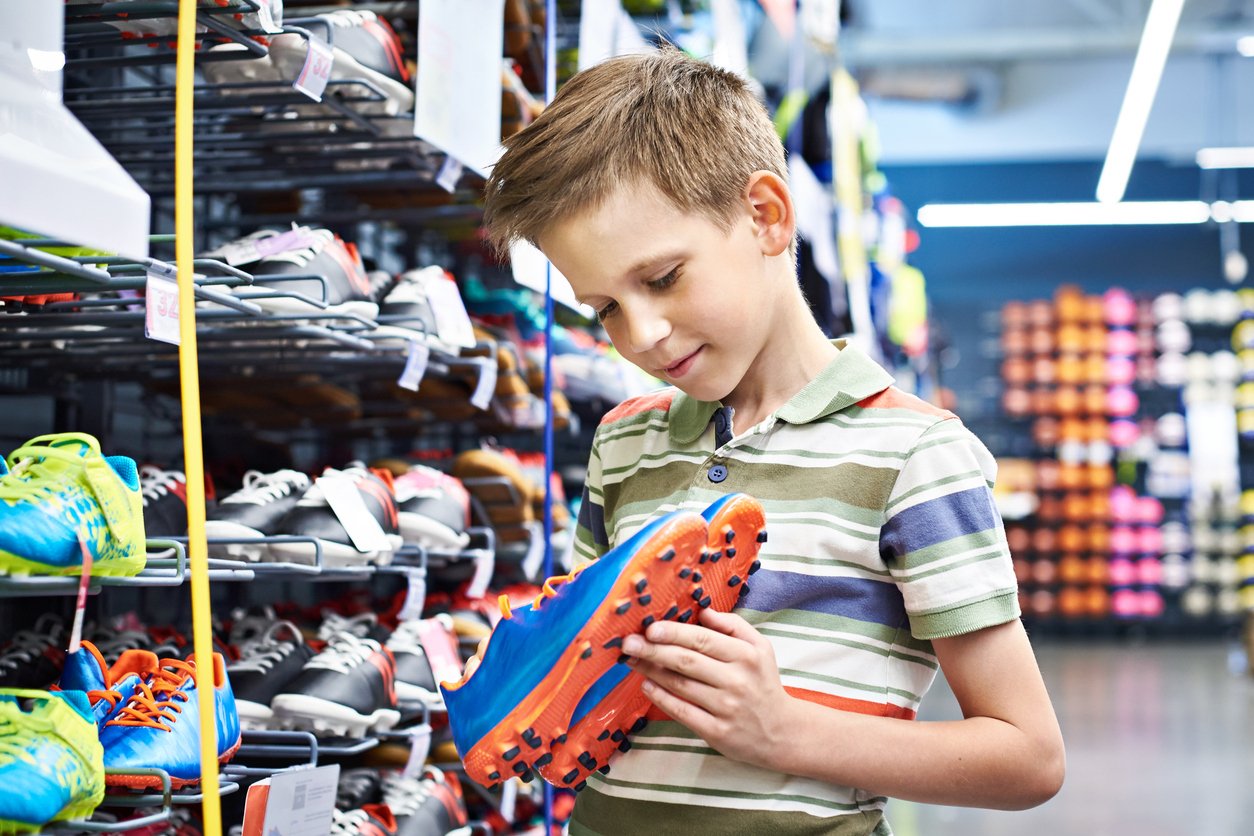 boy choosing a pair of cleats at a sporting goods store