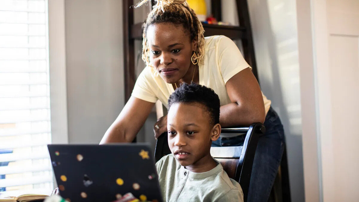 mother with son completing online learning homeschool