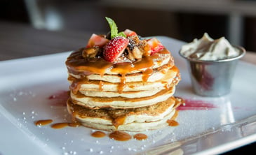 a stack of pancakes with toppings and butter