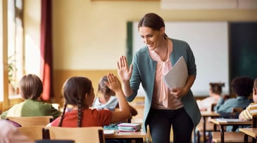 happy teacher and student high fiving in a classroom