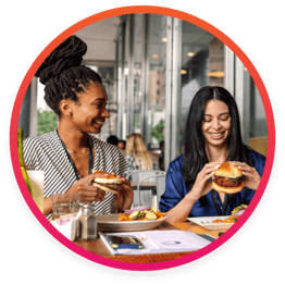 two women eating burgers at a restaurnt