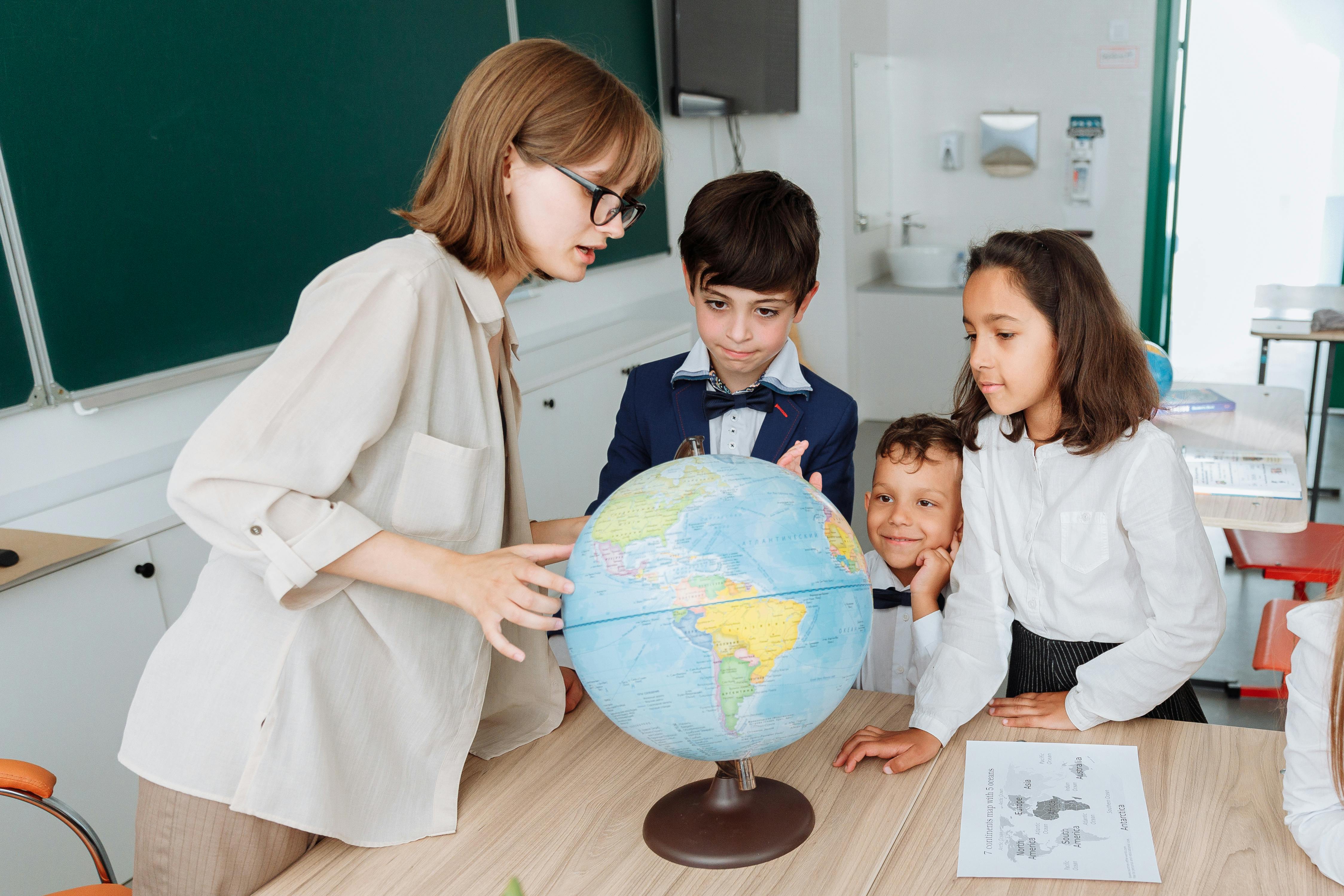 private school teacher educating small group of students about geography
