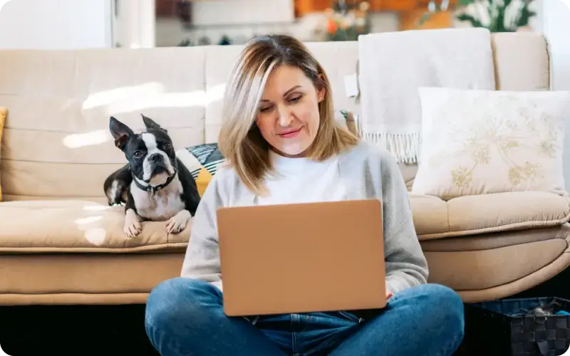 woman working at home on a laptop sitting with her dog