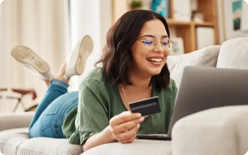 Girl shopping online at home with a credit card in hand