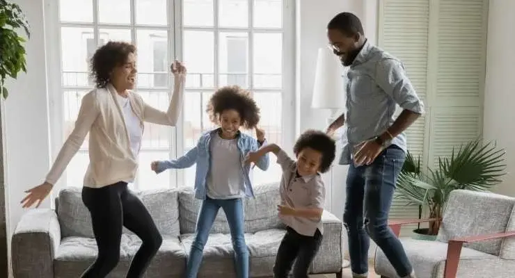 Family of four celebrating and dancing in their living room